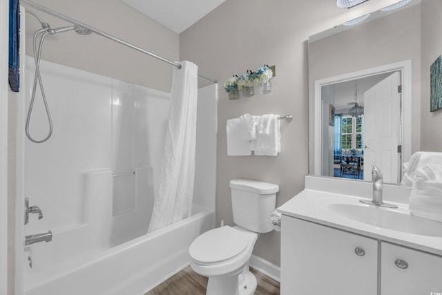 full bath with shower / bath combo, wood finished floors, toilet, vanity, and baseboards