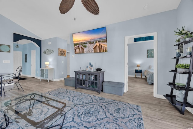 living area featuring arched walkways, ceiling fan, wood finished floors, vaulted ceiling, and baseboards