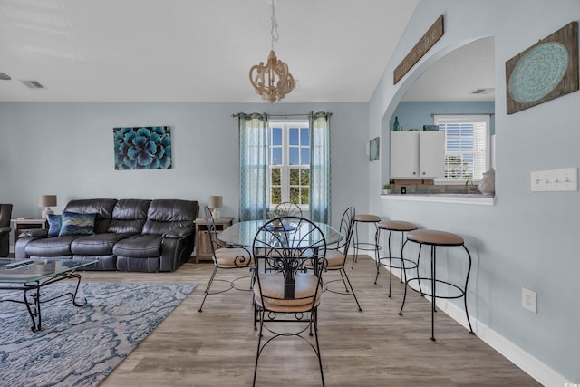 dining room featuring plenty of natural light, wood finished floors, arched walkways, and baseboards