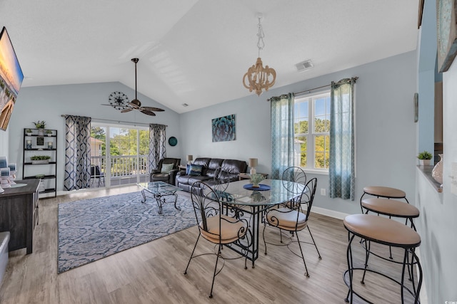 dining area with wood finished floors, vaulted ceiling, a chandelier, a ceiling fan, and baseboards