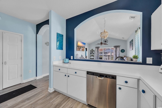kitchen featuring stainless steel dishwasher, arched walkways, light countertops, light wood-type flooring, and white cabinets