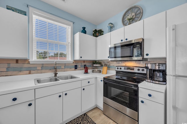 kitchen with appliances with stainless steel finishes, a sink, light countertops, and white cabinets