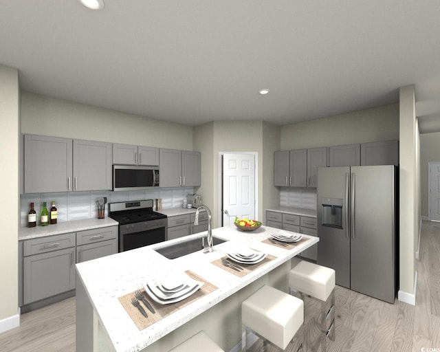 kitchen featuring a sink, light countertops, light wood-style flooring, stainless steel appliances, and gray cabinetry