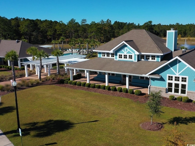exterior space featuring a chimney, a shingled roof, a pergola, and a front yard