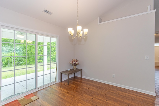spare room featuring wood finished floors, visible vents, a chandelier, and vaulted ceiling