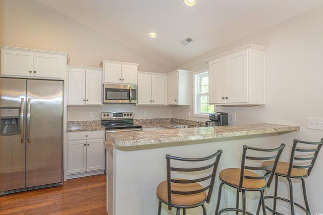 kitchen with stainless steel appliances, light countertops, white cabinetry, a peninsula, and lofted ceiling