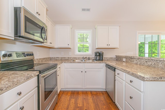 kitchen with a sink, stainless steel appliances, visible vents, a peninsula, and white cabinets