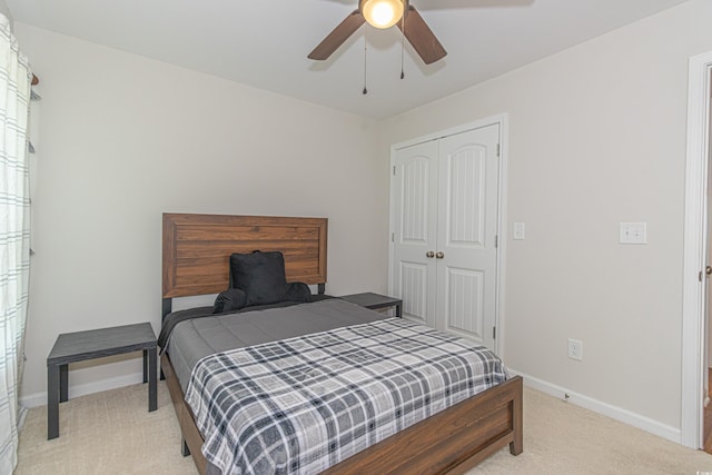 bedroom featuring baseboards, a ceiling fan, light carpet, and a closet