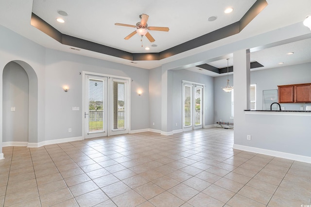 197 Northside Dr, Little River, SC 29566 - unfurnished living room with light tile patterned floors, ceiling fan, plenty of natural light, and a tray ceiling