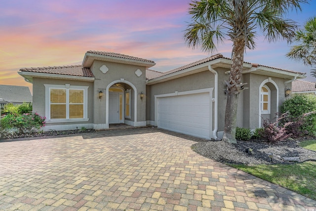 197 Northside Dr, Little River, SC 29566 - mediterranean / spanish house with a garage, stucco siding, decorative driveway, and a tiled roof