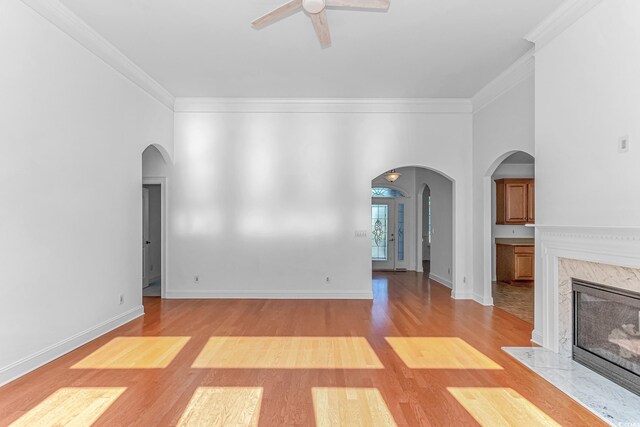 178 Kessinger Dr, Surfside Beach, SC 29575 - unfurnished living room featuring light wood-type flooring, ceiling fan, arched walkways, crown molding, and a high end fireplace