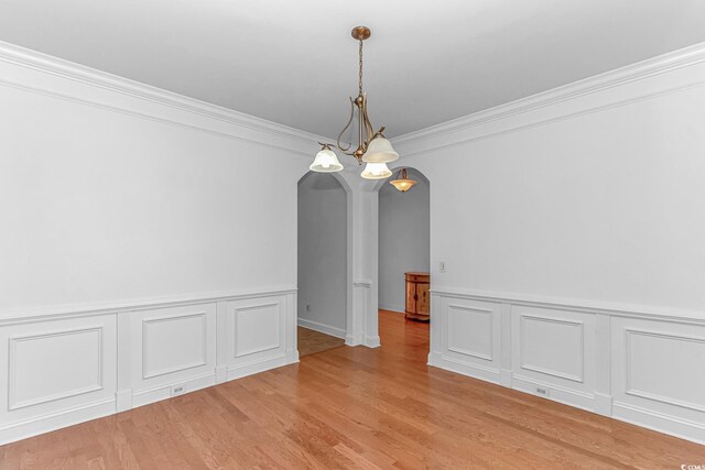 178 Kessinger Dr, Surfside Beach, SC 29575 - empty room with arched walkways, ornamental molding, light wood finished floors, a wainscoted wall, and a decorative wall
