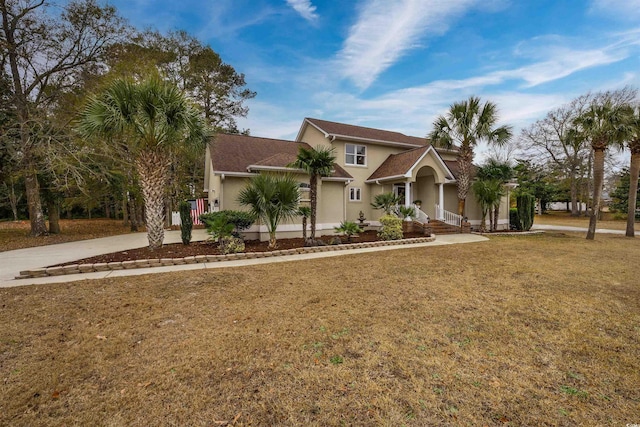 view of front of property with stucco siding, driveway, and a front yard