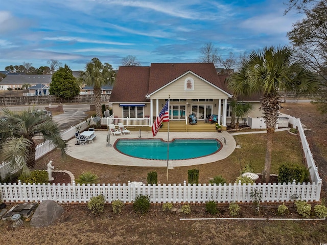 back of house with a fenced in pool, a fenced backyard, and a patio area