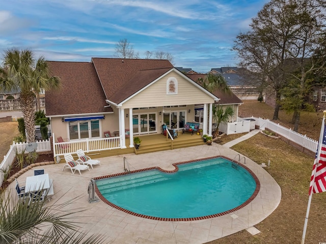 back of property with roof with shingles, stucco siding, a deck, a fenced in pool, and a fenced backyard