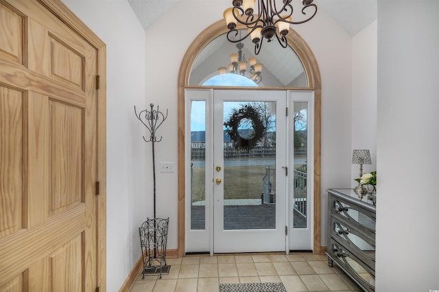 entrance foyer with baseboards, an inviting chandelier, light tile patterned floors, and lofted ceiling