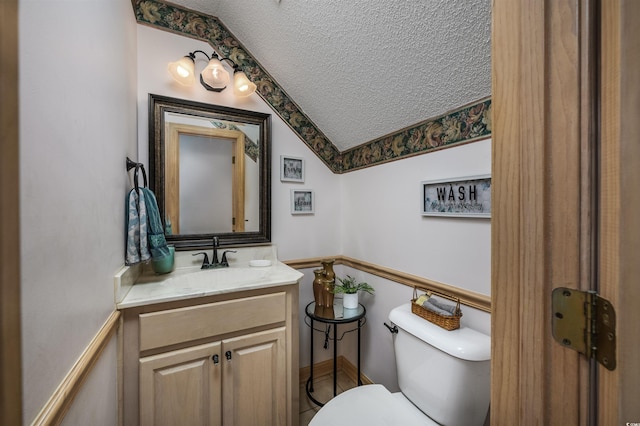 bathroom with vanity, toilet, a textured ceiling, and lofted ceiling