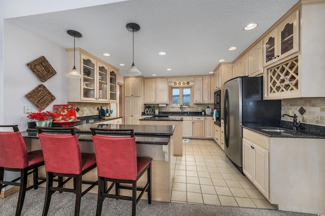kitchen with a sink, a breakfast bar area, black appliances, and glass insert cabinets