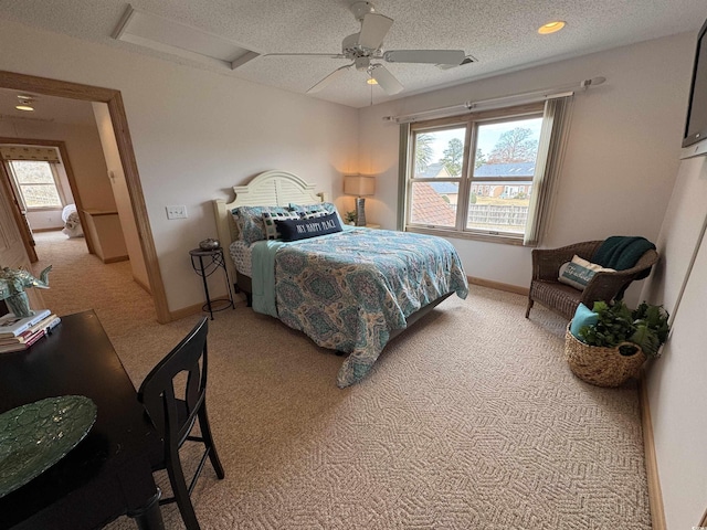 bedroom featuring a ceiling fan, baseboards, light colored carpet, and attic access
