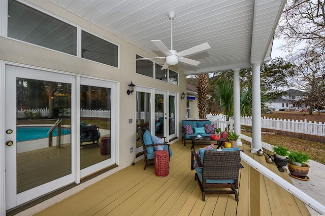 wooden terrace featuring fence, ceiling fan, and an outdoor living space