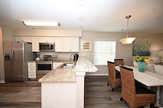 kitchen with white cabinets, stainless steel appliances, a peninsula, a sink, and dark wood finished floors