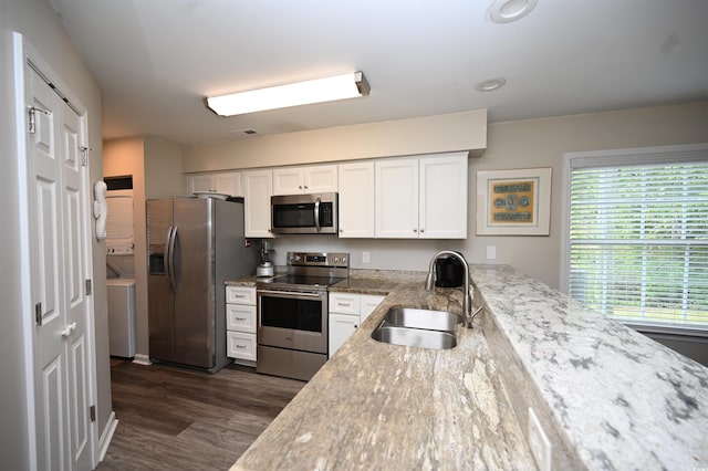 kitchen featuring white cabinets, stainless steel appliances, a sink, washer / clothes dryer, and dark wood-type flooring