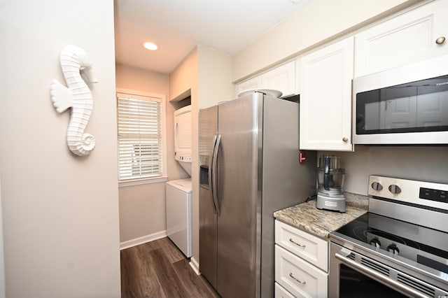 kitchen featuring dark wood-style floors, baseboards, stacked washer and dryer, appliances with stainless steel finishes, and white cabinetry