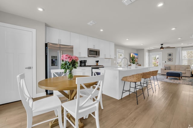 kitchen featuring appliances with stainless steel finishes, a ceiling fan, white cabinets, light wood-style floors, and recessed lighting