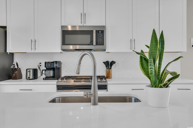 kitchen featuring appliances with stainless steel finishes, light countertops, white cabinets, and decorative backsplash