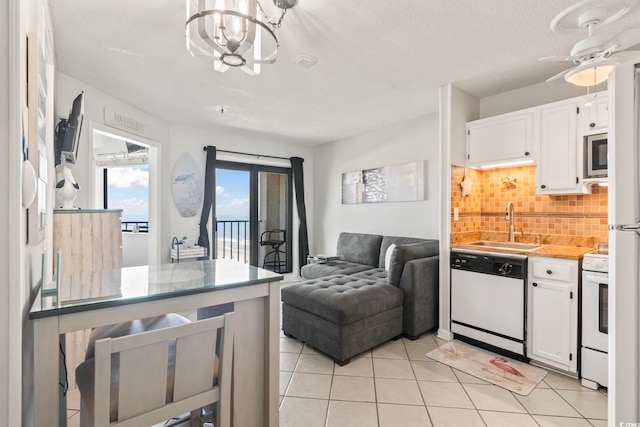 kitchen with a sink, tasteful backsplash, white appliances, and white cabinetry