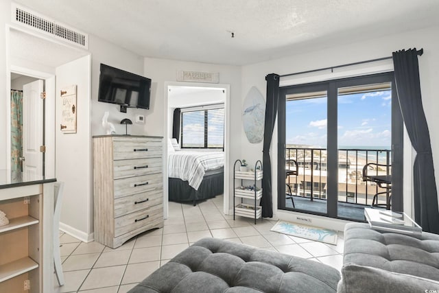 bedroom featuring a textured ceiling, access to exterior, baseboards, light tile patterned floors, and visible vents