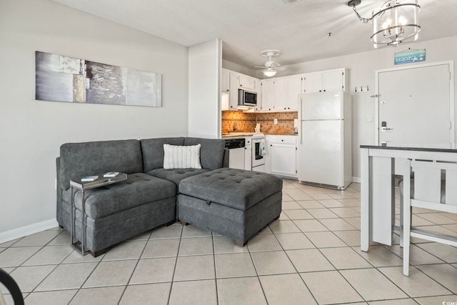 living area featuring baseboards, ceiling fan with notable chandelier, and light tile patterned flooring
