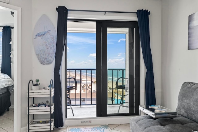 doorway with a water view, a view of the beach, a healthy amount of sunlight, and tile patterned flooring