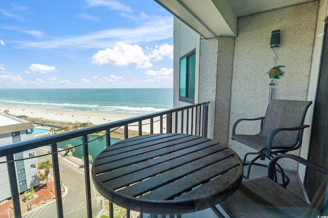 balcony with a water view and a view of the beach