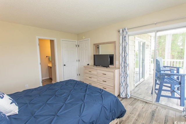 201 Landing Rd Unit D, North Myrtle Beach, SC 29582 - bedroom featuring access to exterior, ensuite bathroom, baseboards, light wood-type flooring, and a textured ceiling