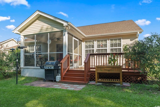 back of property with roof with shingles, a yard, a wooden deck, and a sunroom