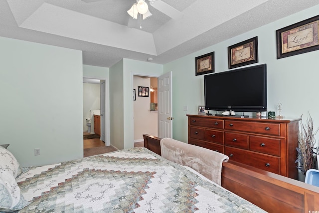 bedroom featuring connected bathroom, a raised ceiling, and ceiling fan