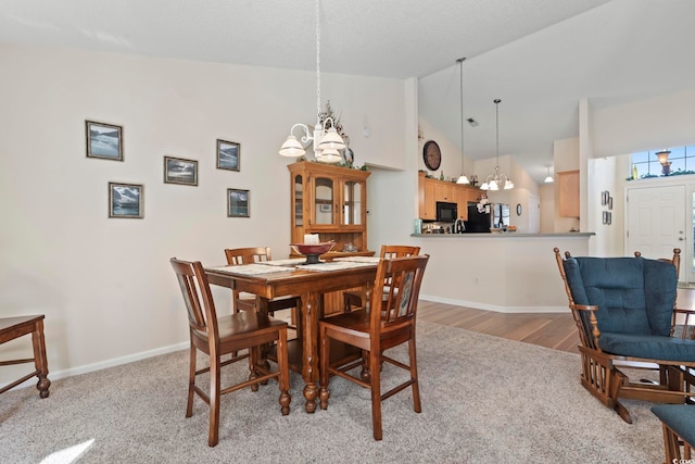 dining area with an inviting chandelier, carpet, baseboards, and high vaulted ceiling