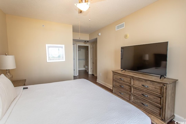 bedroom with a ceiling fan, baseboards, visible vents, and wood finished floors