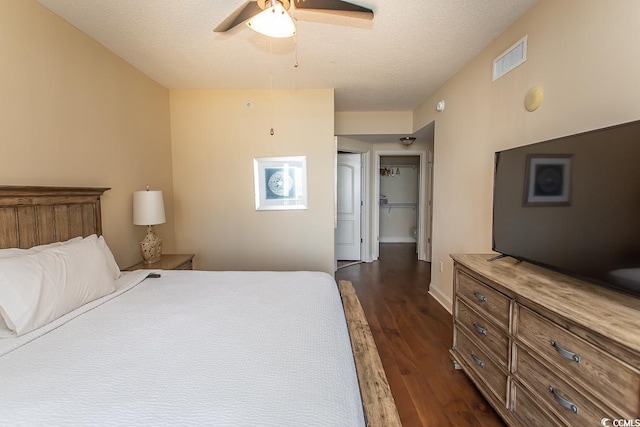 bedroom with dark wood-style flooring, a ceiling fan, visible vents, and a textured ceiling