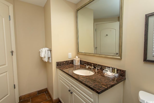 half bathroom featuring toilet, baseboards, and vanity