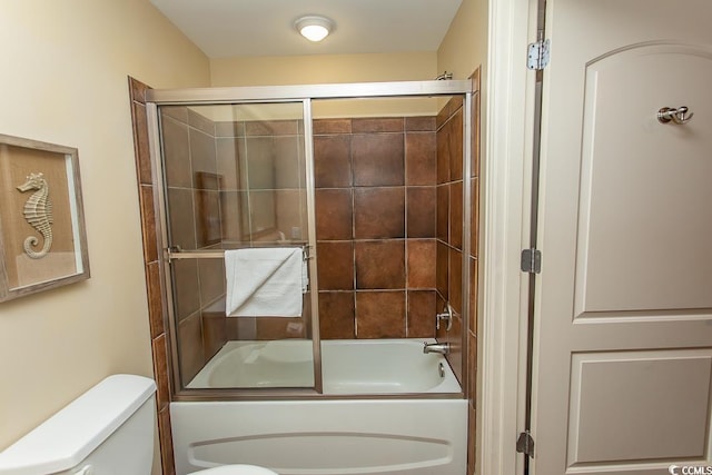 bathroom featuring toilet and shower / bath combination with glass door