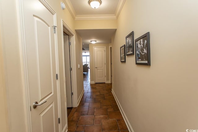 corridor featuring baseboards, ornamental molding, and stone finish floor