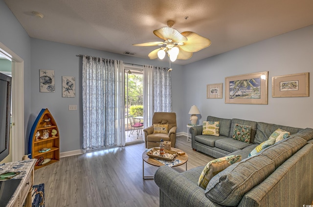living room featuring wood finished floors, visible vents, ceiling fan, and baseboards