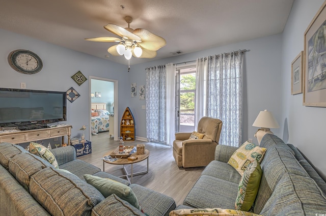 living area featuring visible vents, ceiling fan, wood finished floors, and baseboards