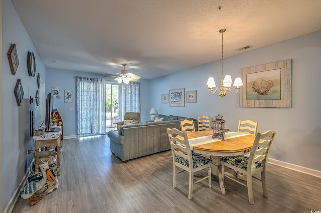 dining room featuring baseboards, visible vents, wood finished floors, and a notable chandelier