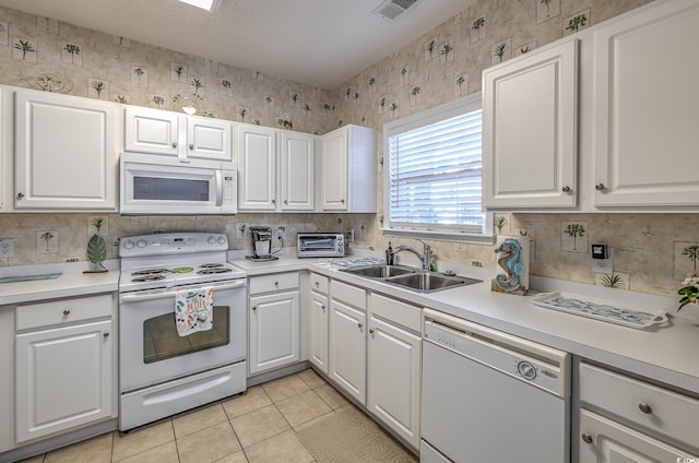 kitchen featuring white appliances, light countertops, wallpapered walls, and a sink