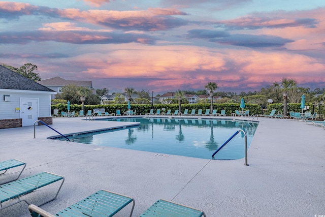 pool at dusk with a community pool and a patio area