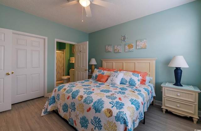 bedroom featuring wood finished floors, a ceiling fan, ensuite bath, and baseboards