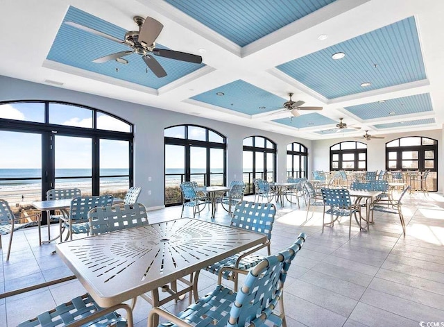 view of patio with outdoor dining space, ceiling fan, a water view, and visible vents